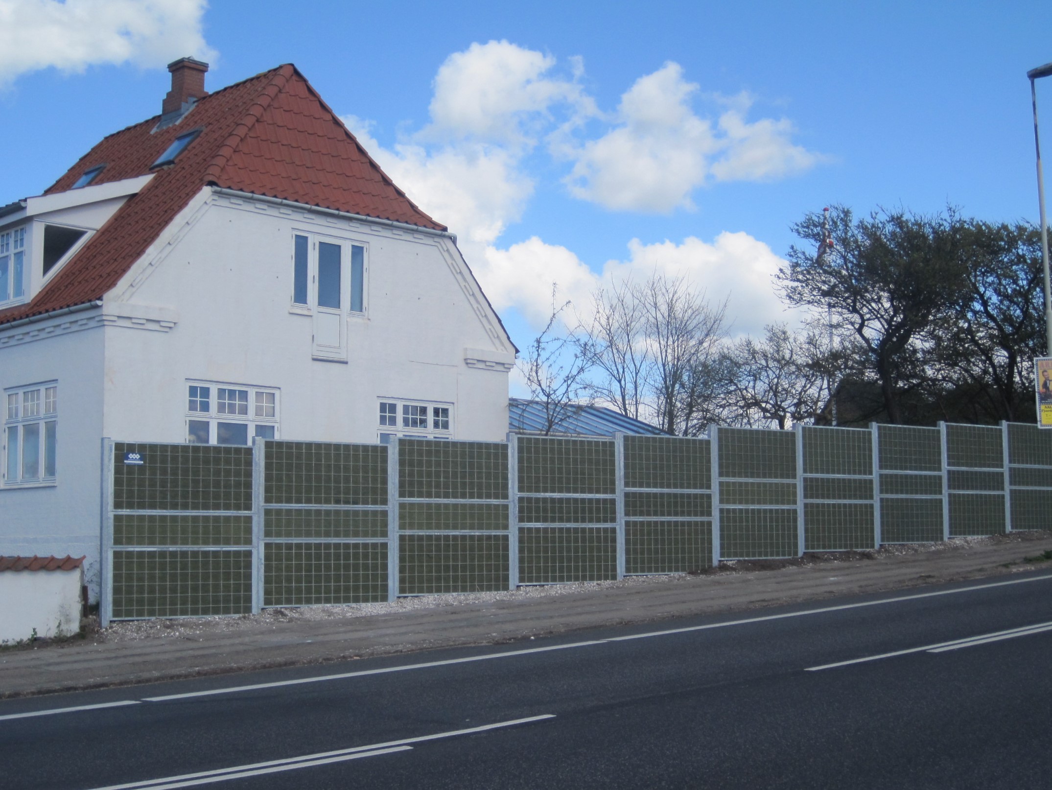 Een Noistop® Steel geluidsscherm van Poda Omheiningen geïnstalleerd voor een huis aan een doorgaande weg om verkeerslawaai te weren